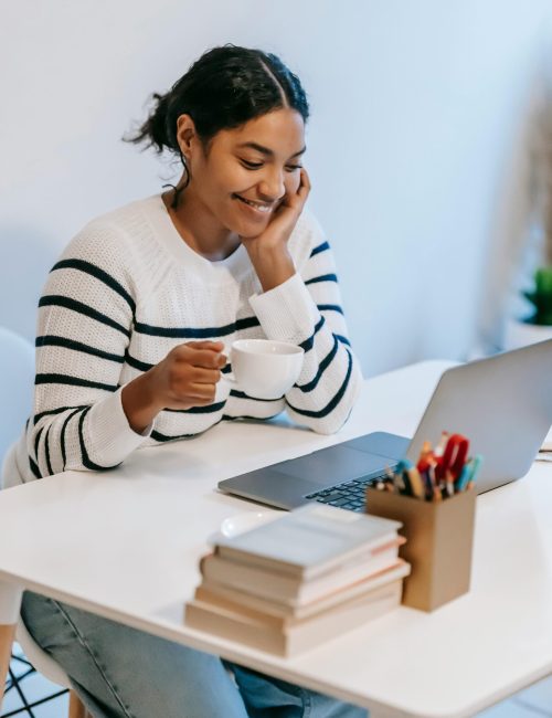 Eine Frau sitzt lächelt vor ihrem Laptop, während sie auf Jobsuche ist