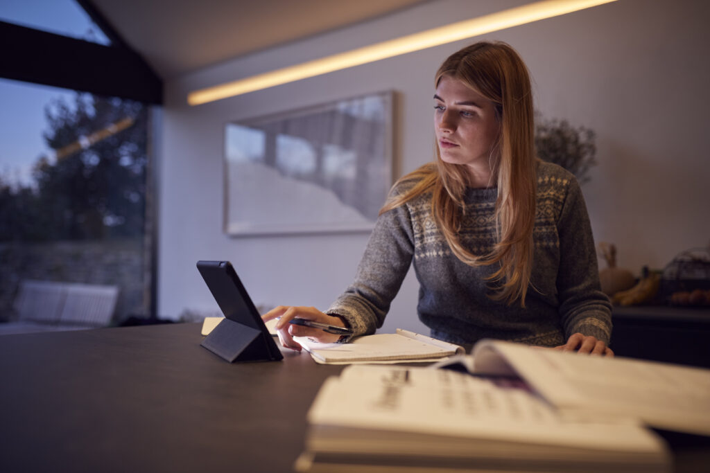 Eine Frau sitzt am Tablet und lernt für ihre kaufmännische Umschulung.