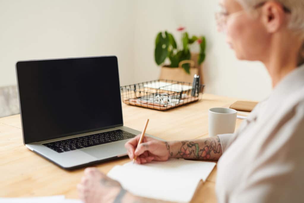 Arbeiten am Laptop mit Stift und Papier