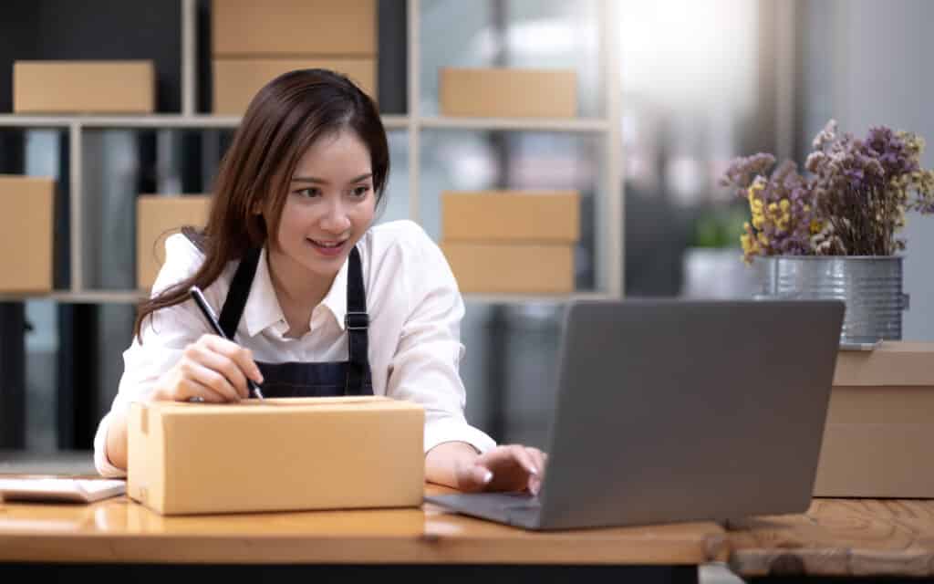 Eine Frau im Online Marketing beschriftet ein Paket