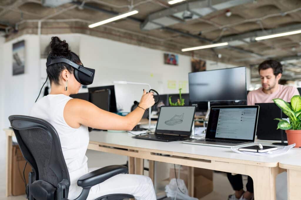 Frau sitzt mit einer VR-Brille am Schreibtisch