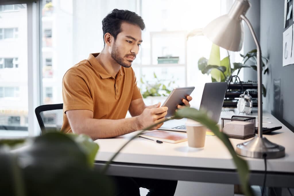 Ein Mann sitzt im Büro am Schreibtisch und arbeitet an der SEO Optimierung